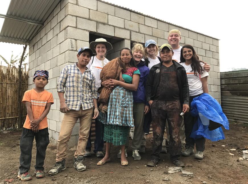 Members of GSL stand alongside the family that will live in the home. The homes are earthquake-proof and include a bedroom, bathroom and shower.